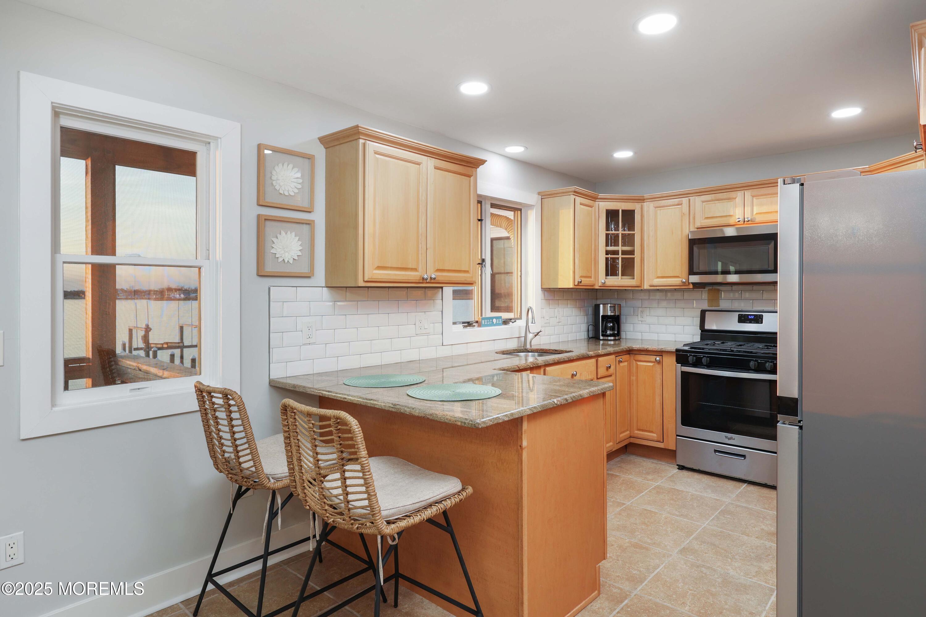 151 Shore Drive Brick, NJ 08723 - Photo 10 of 40 a kitchen with stainless steel appliances granite countertop a stove top oven a sink dishwasher and a refrigerator with wooden floor