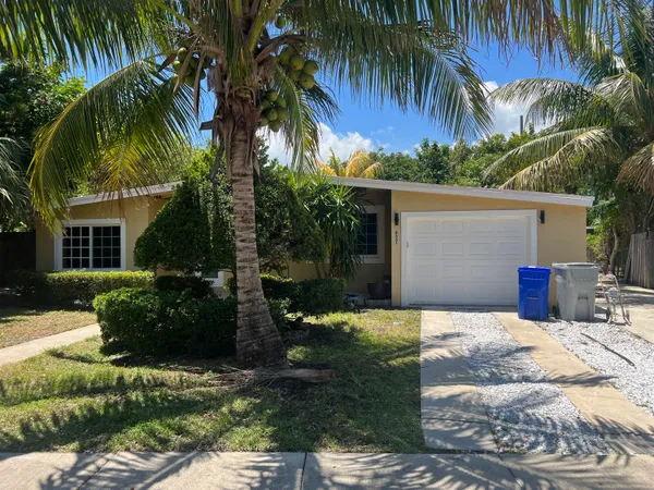 a view of a house with a yard and palm trees
