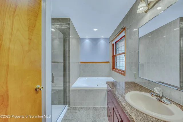 a bathroom with a granite countertop tub sink and mirror