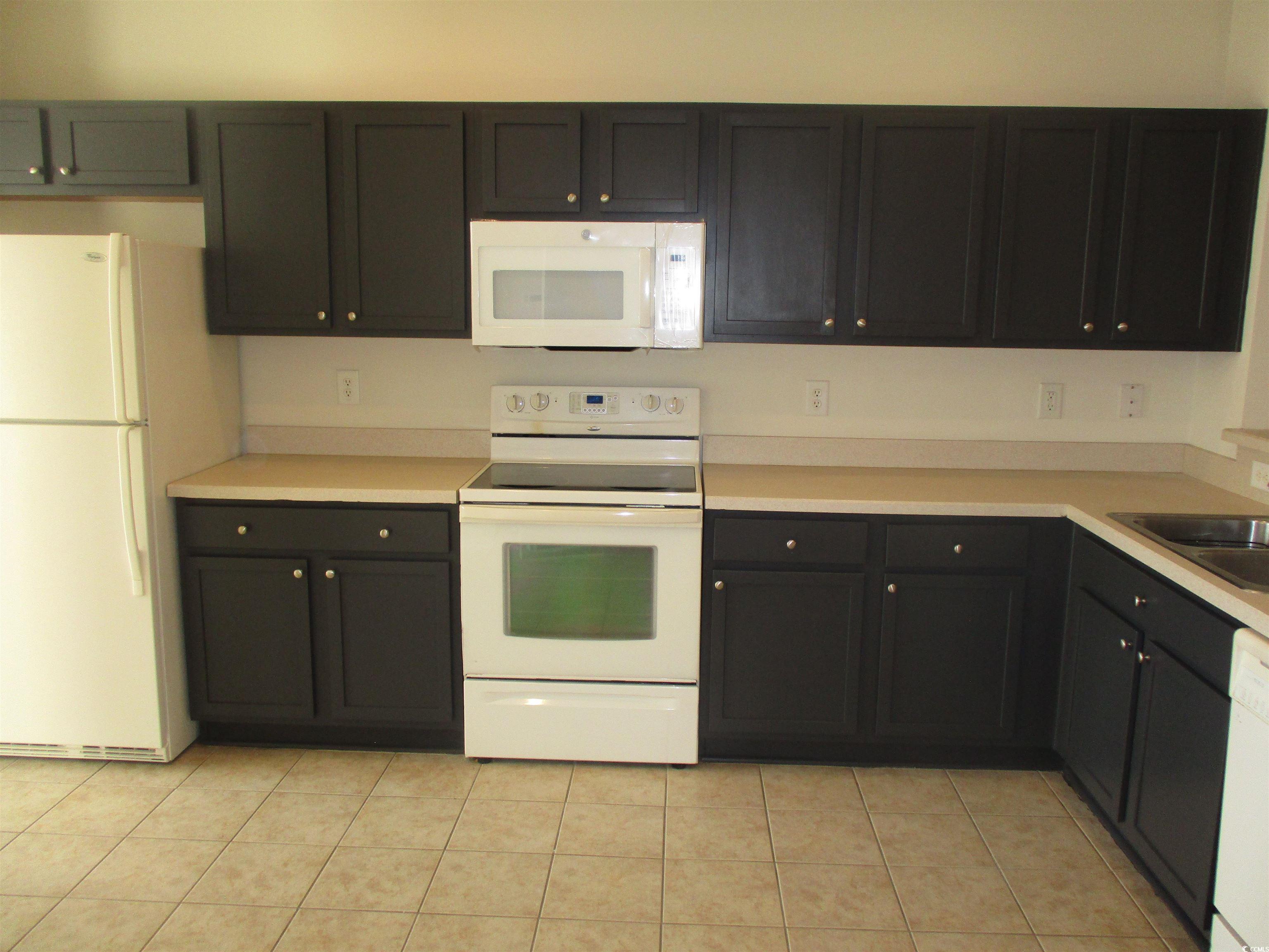 161 Olde Towne Way Myrtle Beach, SC 29588 - Photo 12 of 25 Kitchen featuring white appliances, light countertops, light tile patterned flooring, and dark cabinets