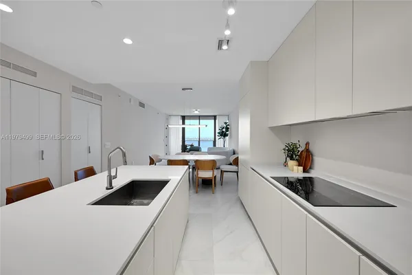 a kitchen that has a lot of cabinets a sink and wooden floor