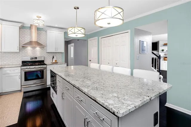 a kitchen with stainless steel appliances a dining table chairs a refrigerator and chandelier