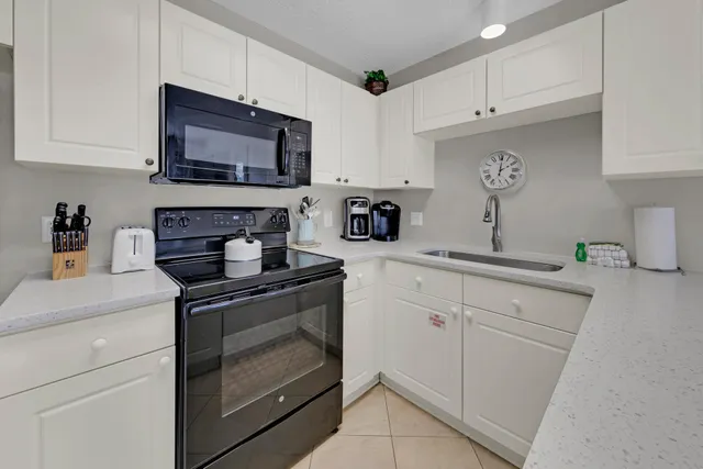 a kitchen with stainless steel appliances granite countertop white cabinets a stove a sink and a microwave