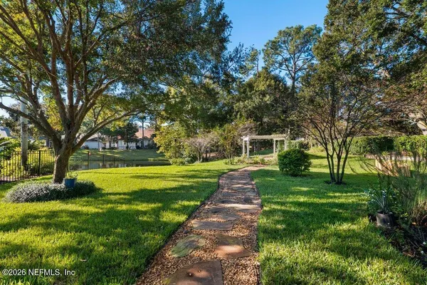 a view of a house with a big yard potted plants and large trees