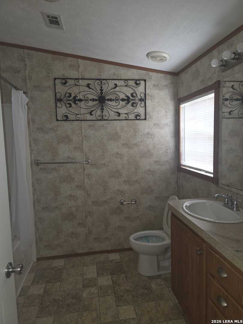 311 East Frio Street Dilley, TX 78017 - Photo 13 of 24 a bathroom with a granite countertop sink a toilet and a shower