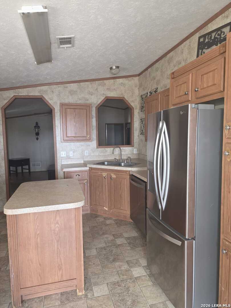 311 East Frio Street Dilley, TX 78017 - Photo 5 of 24 a kitchen with a sink a refrigerator and cabinets
