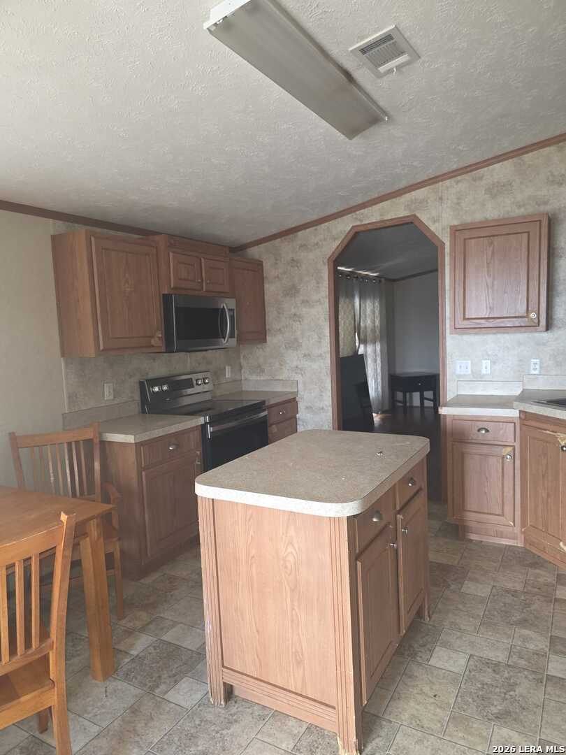 311 East Frio Street Dilley, TX 78017 - Photo 6 of 24 a kitchen with a stove a sink and a refrigerator