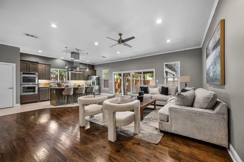 a living room with furniture kitchen view and a wooden floor
