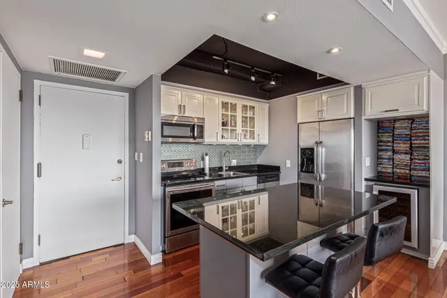 a kitchen with stainless steel appliances granite countertop a refrigerator a stove a sink and a microwave