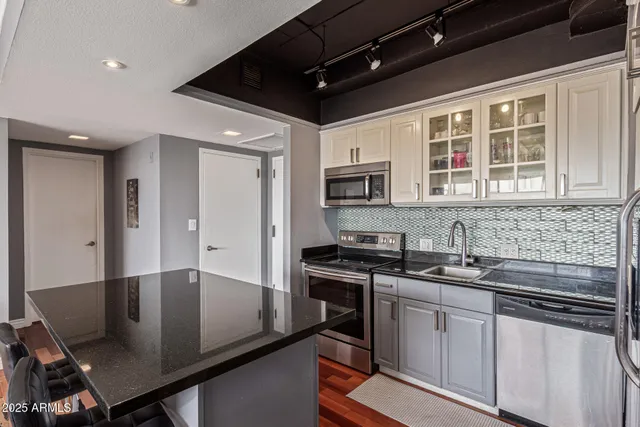a kitchen with stainless steel appliances granite countertop a sink stove and microwave