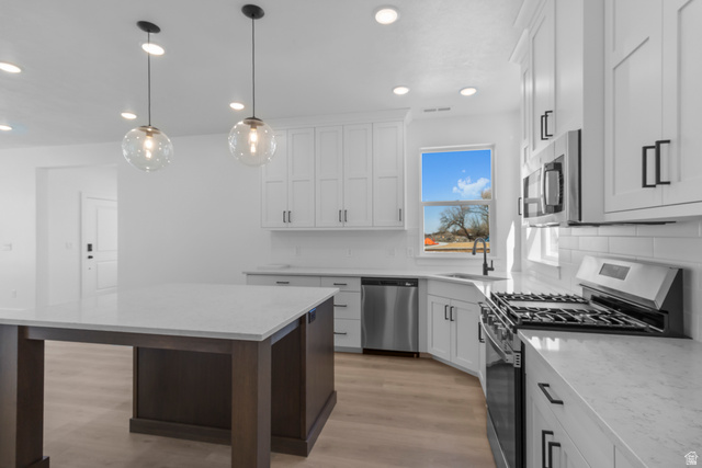 248 West 2920th Street South Logan, UT 84321 - Photo 20 of 47 Kitchen featuring white shaker cabinetry, stainless steel appliances, a center island with a light-toned countertop, wood-finish flooring, and pendant lighting