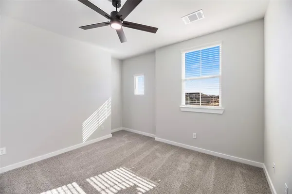 an empty room with a ceiling fan and windows