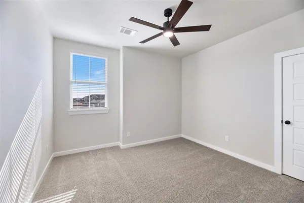 an empty room with a ceiling fan and window