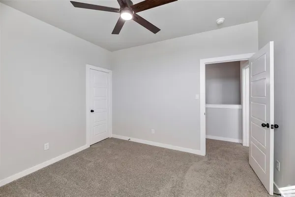 an empty room with closet and a chandelier fan