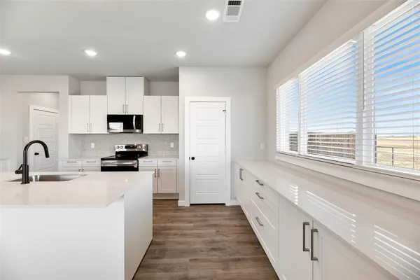 a kitchen with granite countertop a sink a counter space appliances and cabinets