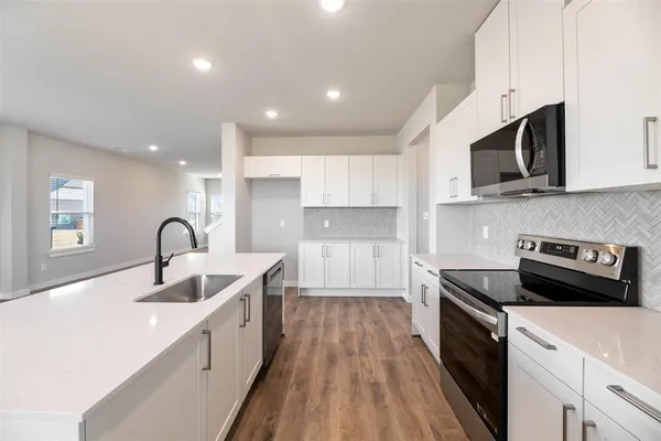 a kitchen with stainless steel appliances granite countertop a sink dishwasher a stove and a microwave oven with wooden floor