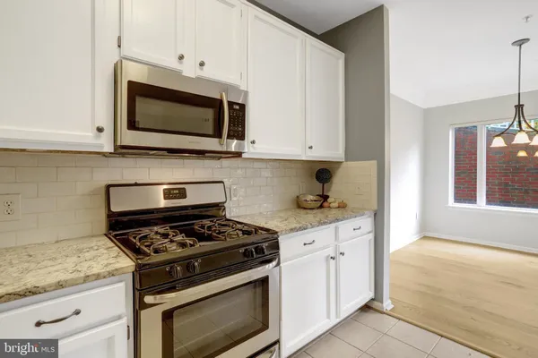 a kitchen with stainless steel appliances white cabinets and a stove a oven with white countertops