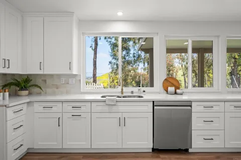 a kitchen with granite countertop white cabinets and a window