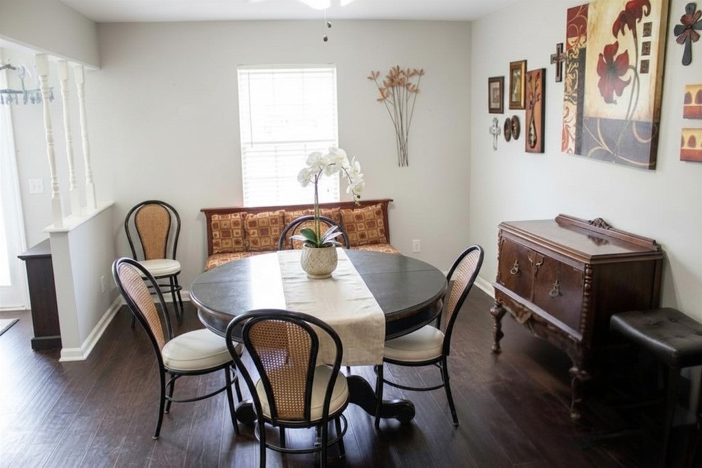 206 Riverside Street Highlands, TX 77562 - Photo 5 of 12 Charming formal dining area with dark laminate flooring, decorative white columns framing the entry, and great natural light, an elegant space for everyday meals or entertaining guests.