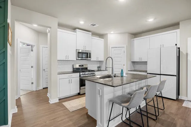 a kitchen with stainless steel appliances granite countertop a stove a sink a refrigerator a microwave and cabinets