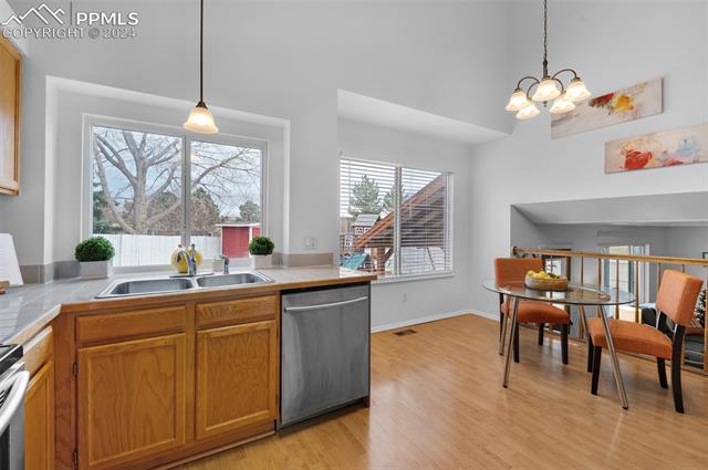7803 Swiftrun Road Colorado Springs, CO 80920 - Photo 7 of 41 Kitchen featuring appliances with stainless steel finishes, sink, tile counters, light hardwood / wood-style floors, and hanging light fixtures