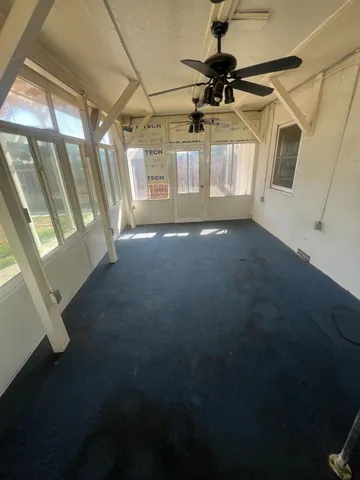 a view of empty room with wooden floor and fan