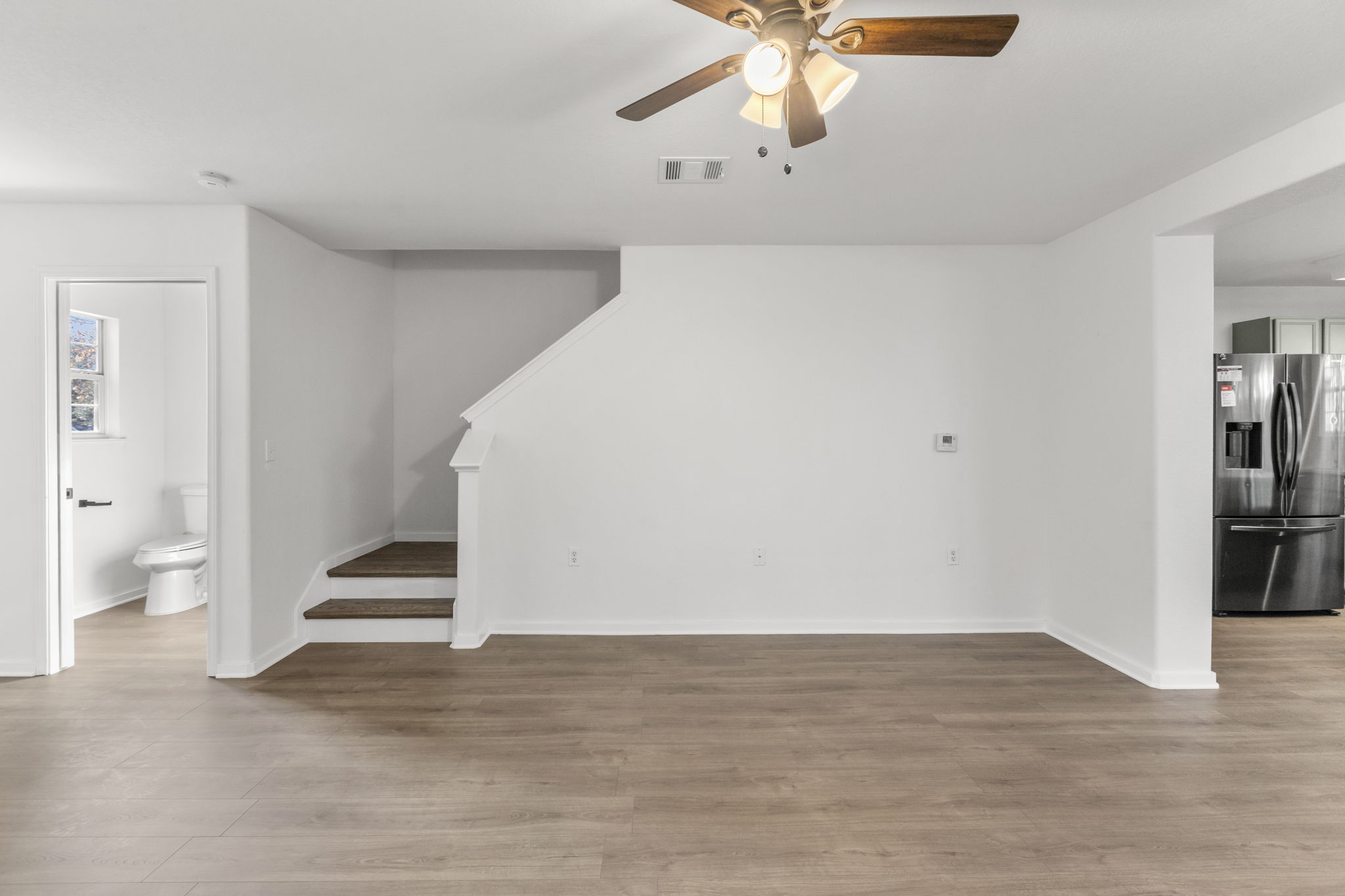 2110 Nogales Trail Austin, TX 78744 - Photo 6 of 37 a view of an empty room with wooden floor and a ceiling fan