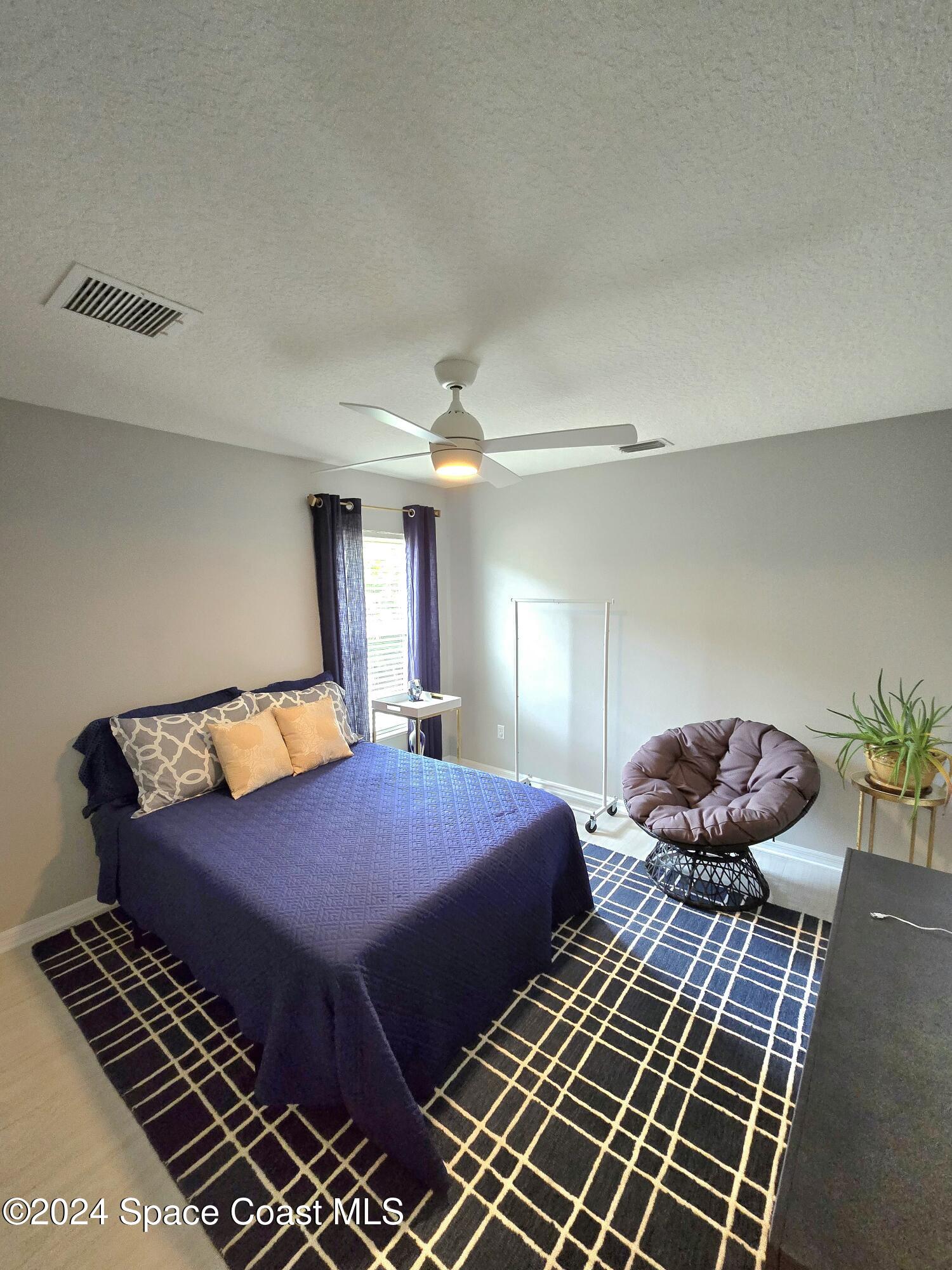 491 South Key Lime Square Southwest Vero Beach, FL 32968 - Photo 18 of 29 a bedroom with a bed and a chandelier