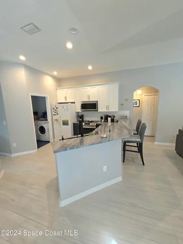 a living room with furniture and a dining table with kitchen view