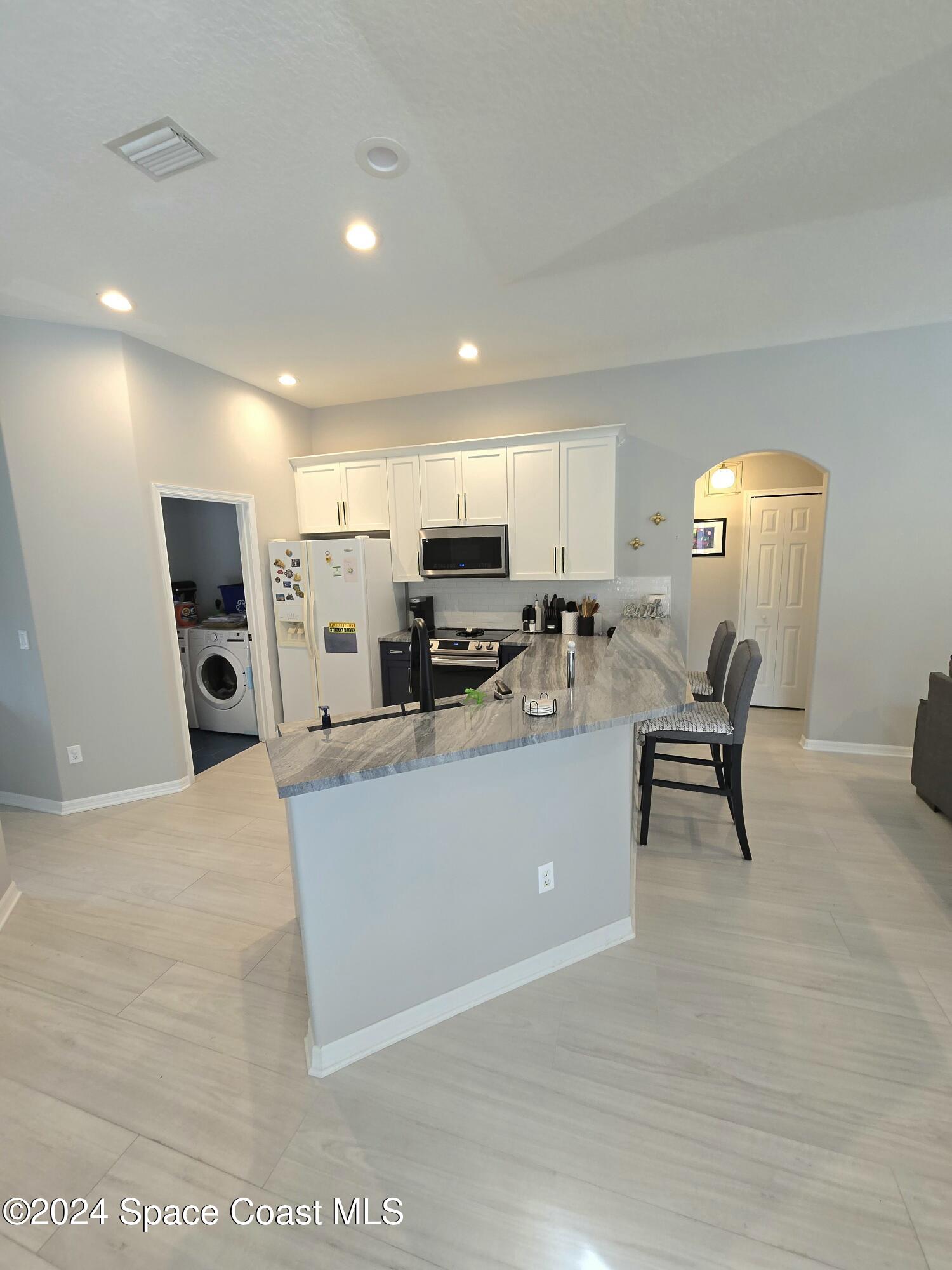 491 South Key Lime Square Southwest Vero Beach, FL 32968 - Photo 6 of 29 a living room with furniture and a dining table with kitchen view