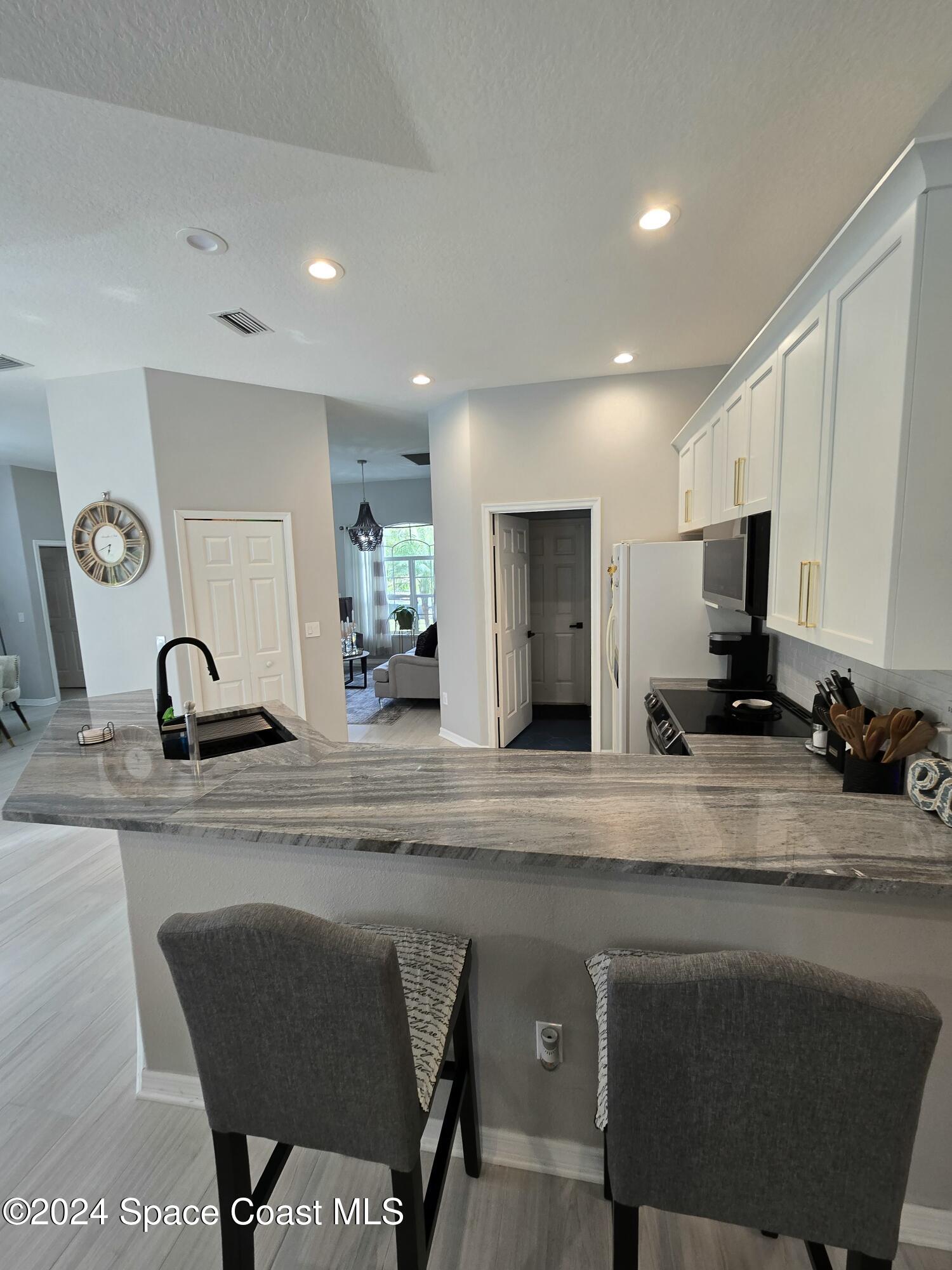 491 South Key Lime Square Southwest Vero Beach, FL 32968 - Photo 8 of 29 a kitchen with a dining table chairs and refrigerator