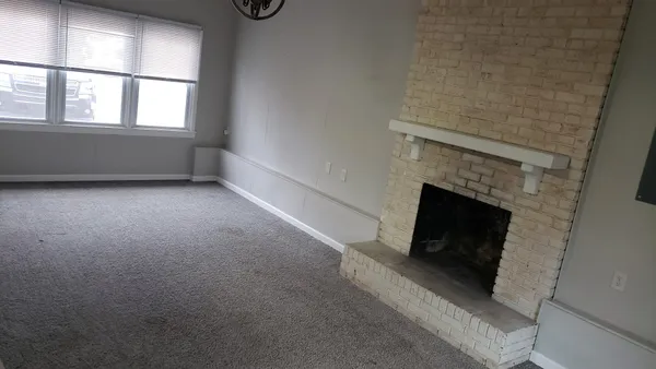 an empty room with windows and fireplace