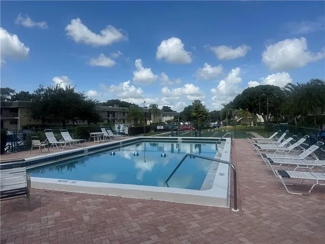 a view of swimming pool with outdoor seating and plants in back