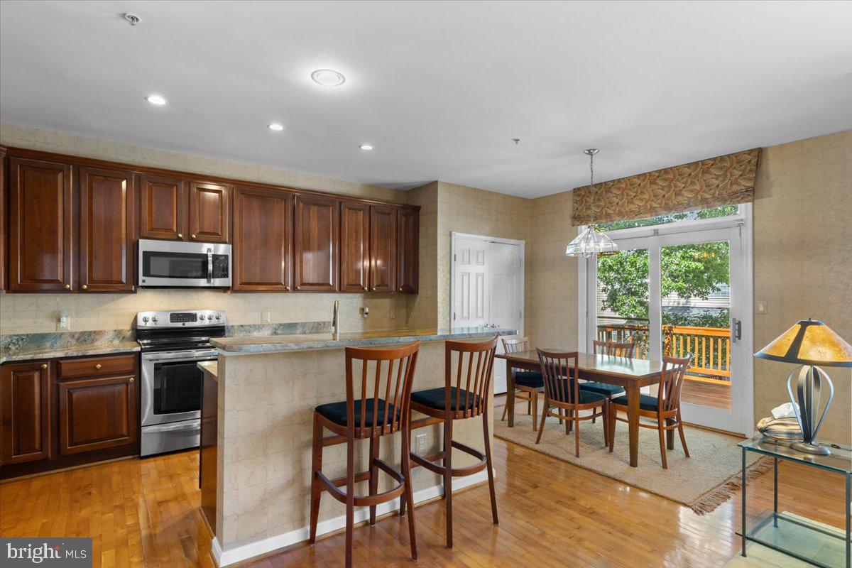 46134 Brisbane Square Sterling, VA 20165 - Photo 14 of 48 a kitchen with stainless steel appliances granite countertop a stove top oven a sink dishwasher a dining table and chairs with wooden floor