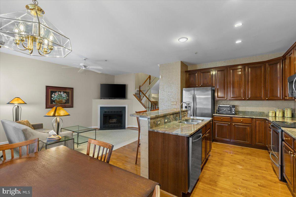 46134 Brisbane Square Sterling, VA 20165 - Photo 17 of 48 a kitchen with stainless steel appliances granite countertop a stove top oven a sink a dining table and chairs with wooden floor