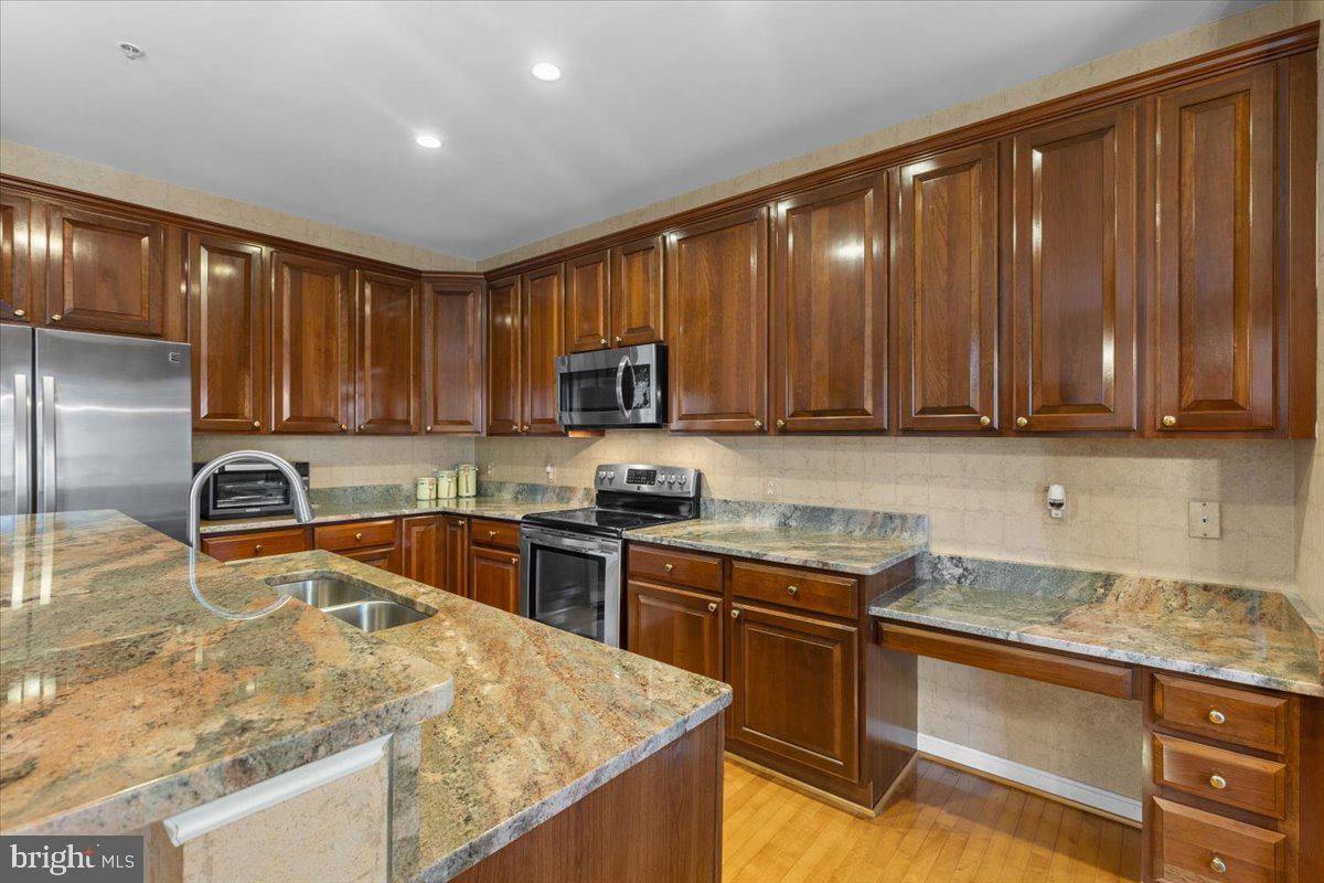 46134 Brisbane Square Sterling, VA 20165 - Photo 18 of 48 a kitchen with stainless steel appliances granite countertop wooden cabinets a stove top oven a sink and dishwasher