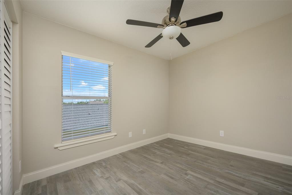 6227 Blue Runner Court Lakewood Ranch, FL 34202 - Photo 26 of 46 an empty room with wooden floor ceiling fan and windows