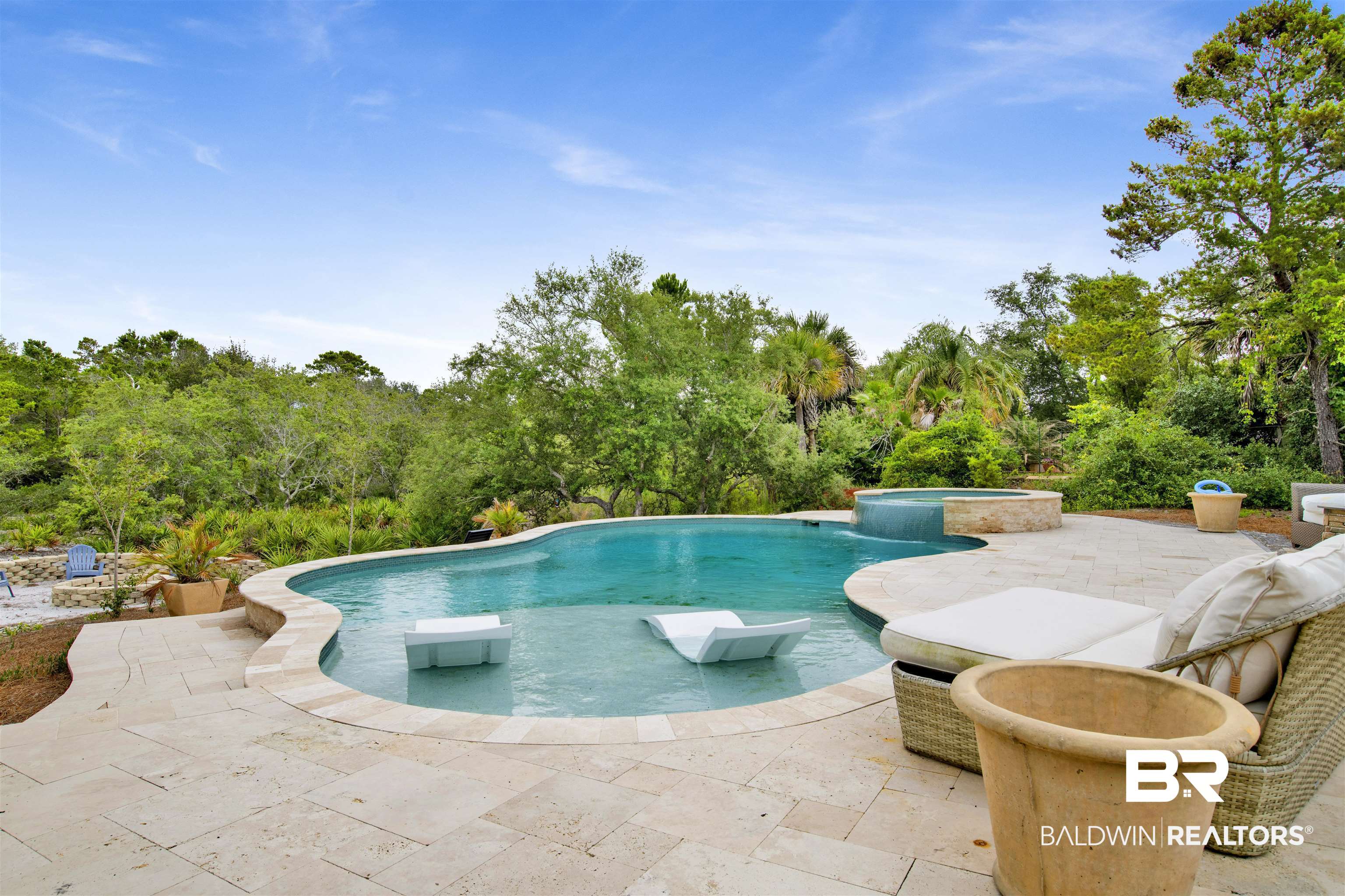 30351 River Road Orange Beach, AL 36561 - Photo 5 of 44 Freeform swimming pool featuring an integrated spa with waterfall, sun shelf, and natural stone paver decking