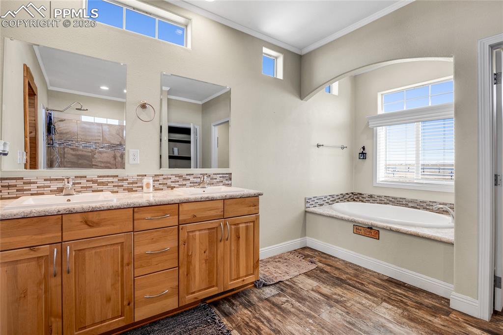 7880 J D Johnson Road Peyton, CO 80831 - Photo 10 of 50 Full bathroom with double vanity, a bath, a tile shower, dark wood-style floors, and ornamental molding