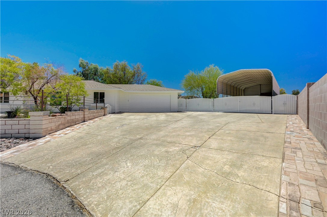 7631 Bermuda Road Las Vegas, NV 89123 - Photo 4 of 64 A spacious concrete driveway leads to a welcoming residence with an attached garage and a detached covered structure.