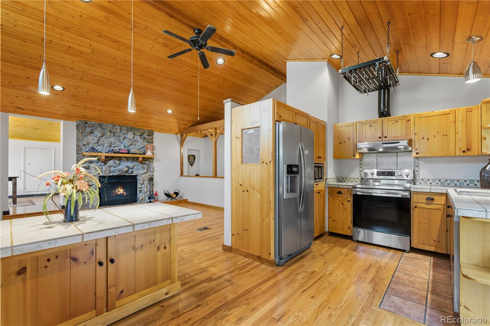 401 Lake Road Idaho Springs, CO 80452 - Photo 3 of 47 a kitchen with stainless steel appliances kitchen island granite countertop a refrigerator a stove a sink dishwasher and wooden cabinets with wooden floor