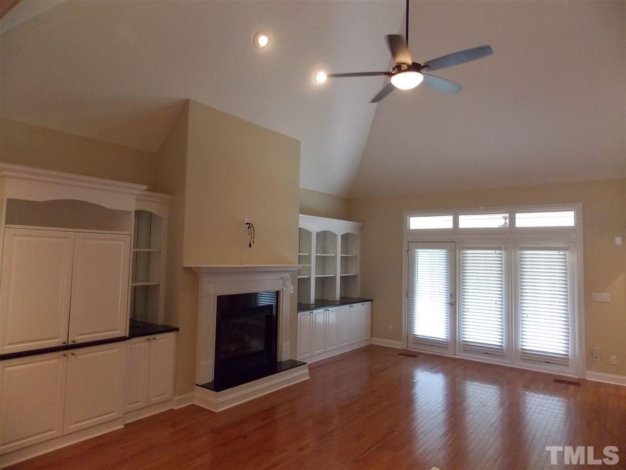 12233 Beestone Lane Raleigh, NC 27614 - Photo 4 of 25 a view of a livingroom with a fireplace a chandelier and wooden floor