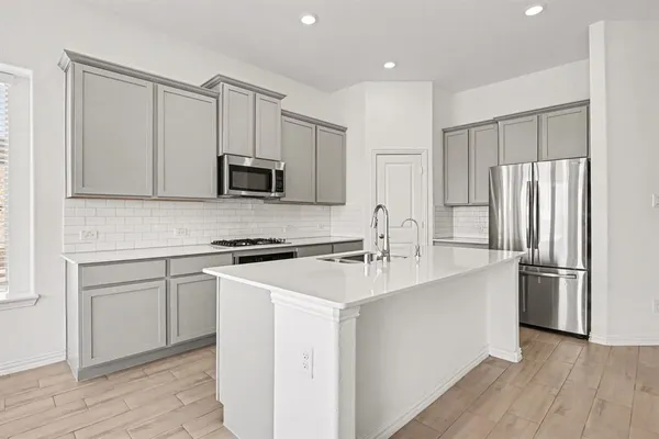 a kitchen with stainless steel appliances granite countertop a refrigerator stove a sink and white cabinets