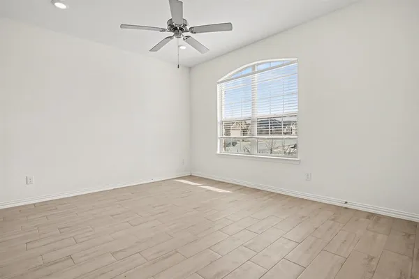 an empty room with windows and fan
