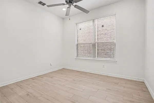 an empty room with a window and a ceiling fan