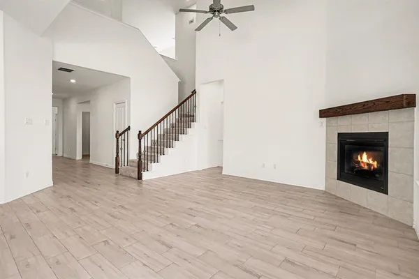 a view of an empty room with wooden floor fireplace and a window