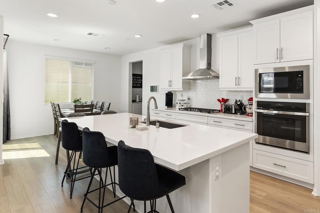 32257 Jeter Lane Menifee, CA 92584 - Photo 8 of 33 a kitchen with stainless steel appliances a stove a sink a microwave a refrigerator and white cabinets with wooden floor