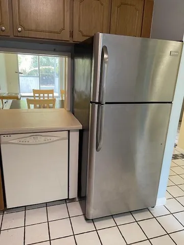 a view of a refrigerator in kitchen and a window