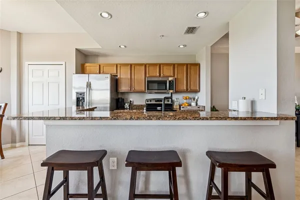 a kitchen with stainless steel appliances kitchen island granite countertop a refrigerator and a stove top oven