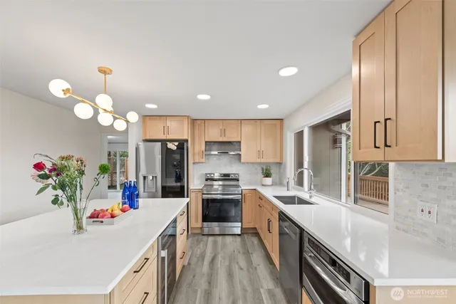 a kitchen with kitchen island granite countertop a sink cabinets and stainless steel appliances